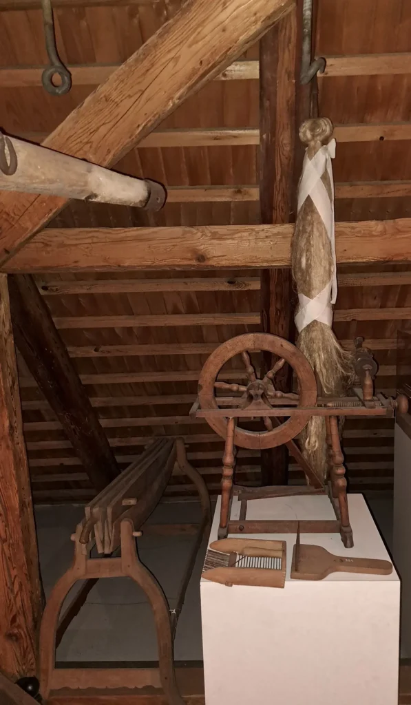 Historisches Spinnrad mit aufgehängten Flachsfasern in einem Dachraum