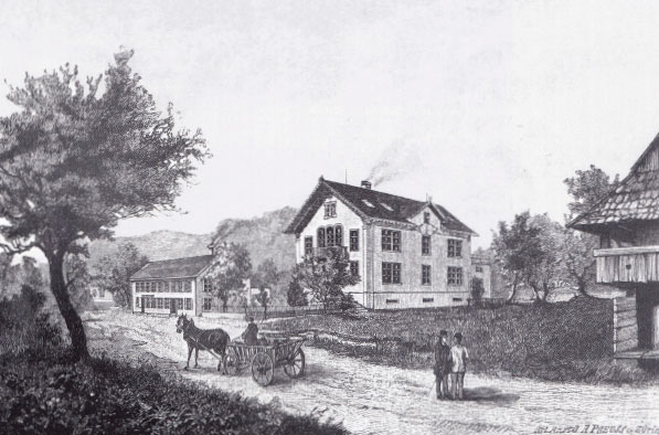 Zu sehen ist ein altes schwarz/weiss Bild der Bally Fabrik. Davor Ross und Wagen sowie Fussgänger.