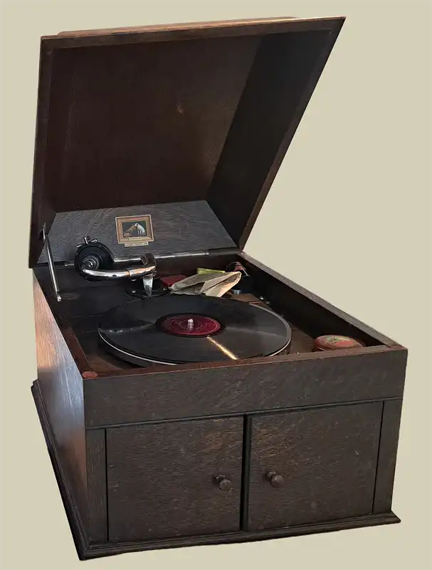 Grammophon in einem dunklen Holzgehäuse mit geöffnetem Deckel, aufgelegter Schallplatte und Tonarm.