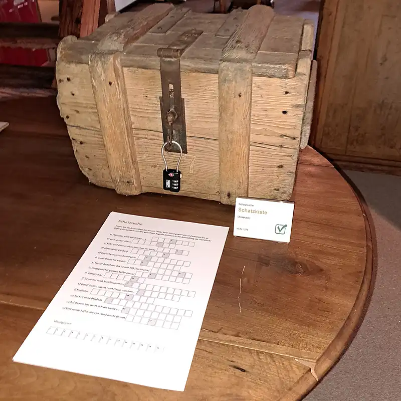 Hölzerne Schatzkiste mit Zahlenschloss und bereitliegendem Rätselblatt im Museum Chornhuus.